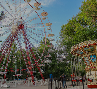 Колесо обозрения и ретро-карусель среди зелени в парке Central Park