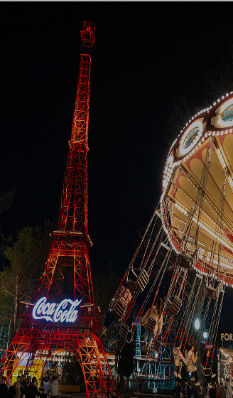 Светящаяся башня Coca-Cola и вращающаяся карусель ночью в парке Central Park